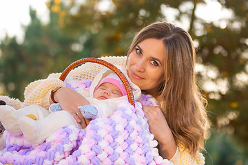 Image showing Mom hugs baby sleeping in basket