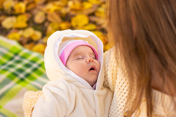 Image showing Two-month-old baby sleeps in mom\'s arms