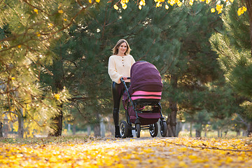 Image showing Young mother with a stroller walks in the autumn square