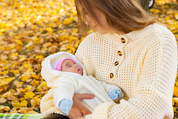 Image showing Mom holds baby in her arms on walk in autumn park