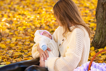 Image showing Mom crouched in the park, walking with a newborn baby