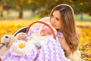 Image showing Mom relaxes with newborn baby in park