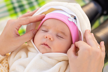 Image showing Mom fixes the cap of a two-month-old baby