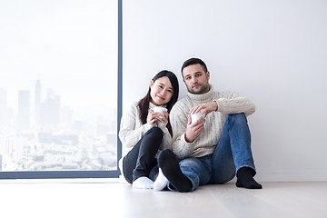 Image showing multiethnic couple enjoying morning coffee by the window