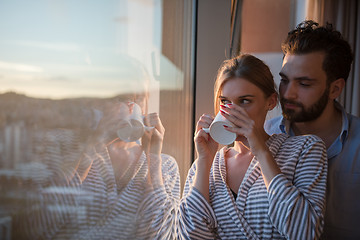 Image showing young couple enjoying evening coffee by the window