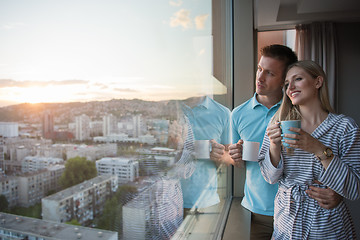 Image showing young couple enjoying evening coffee by the window