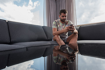 Image showing young casual man using a mobile phone at home