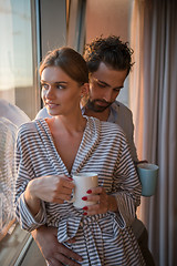 Image showing young couple enjoying evening coffee by the window