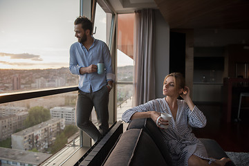 Image showing young couple enjoying evening coffee by the window