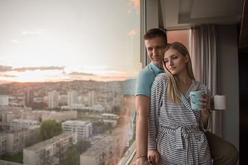 Image showing young couple enjoying evening coffee by the window