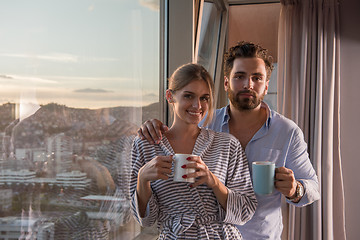 Image showing young couple enjoying evening coffee by the window