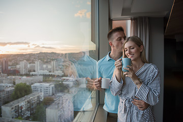 Image showing young couple enjoying evening coffee by the window