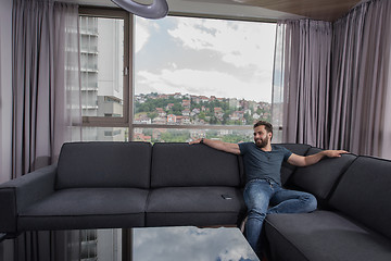 Image showing young casual man using a mobile phone at home