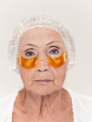 Image showing Senior woman studio isolated on white wall beauty concept looking at camera making masks under eyes