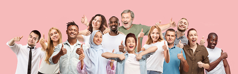 Image showing The happy business women and men standing and smiling against pink background.