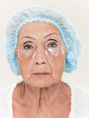 Image showing Senior woman studio isolated on white wall beauty concept looking at camera making masks under eyes