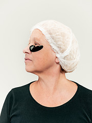 Image showing Senior woman studio looking at camera making masks under eyes
