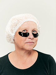 Image showing Senior woman studio looking at camera making masks under eyes