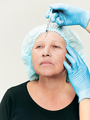 Image showing surgeon doing skin check on mid age woman before plastic surgery