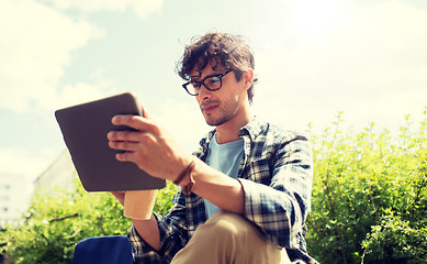 Image showing man in glasses with tablet pc on city street