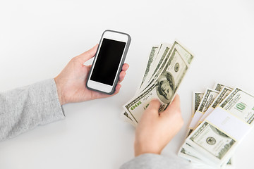 Image showing close up of hands with smartphone and dollar money