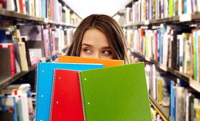 Image showing teenage student girl behind notebooks at library