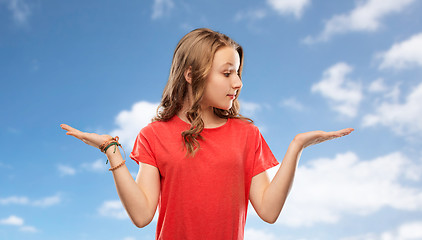 Image showing smiling teenage girl holding empty hand over sky