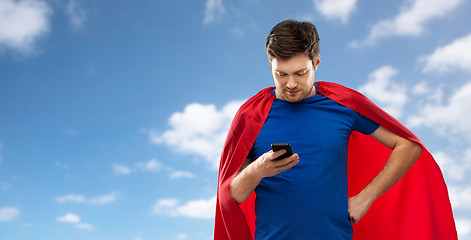 Image showing man in red superhero cape with smartphone over sky