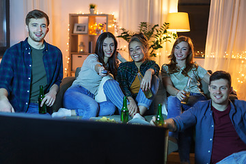 Image showing happy friends with drinks watching tv at home