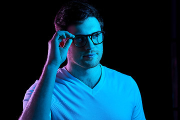 Image showing man in glasses over neon lights in dark room