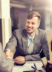 Image showing smiling businessman making handshake at office