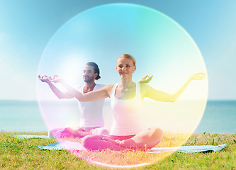 Image showing couple doing yoga in lotus pose with rainbow aura