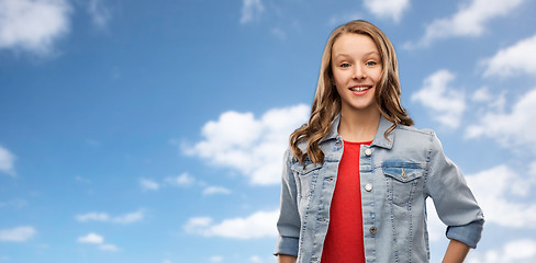 Image showing smiling teenage girl in denim jacket over sky