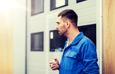 Image showing auto mechanic smoking cigarette at car workshop