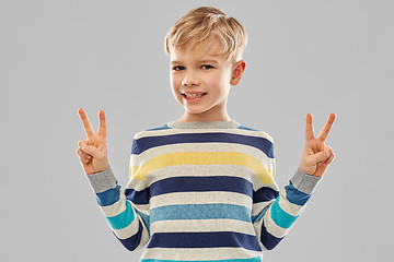 Image showing smiling boy in striped pullover showing peace