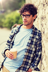 Image showing man in eyeglasses drinking coffee over street wall