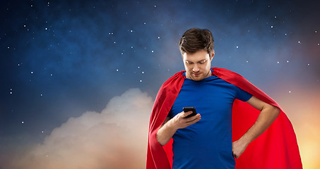 Image showing young man in red superhero cape using smartphone