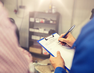 Image showing auto mechanic with clipboard and man at car shop