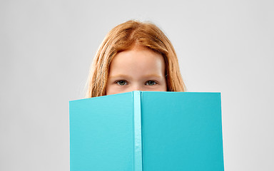 Image showing smiling red haired girl reading book