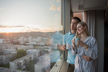 Image showing young couple enjoying evening coffee by the window
