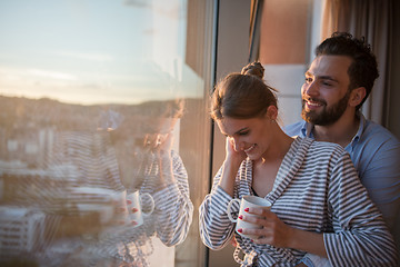 Image showing young couple enjoying evening coffee by the window