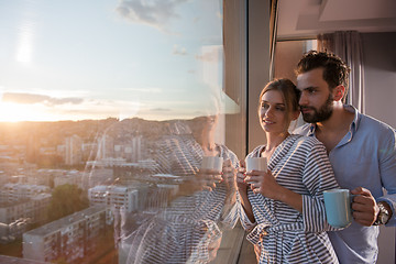 Image showing young couple enjoying evening coffee by the window