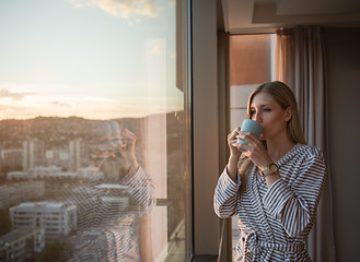 Image showing young woman enjoying evening coffee by the window