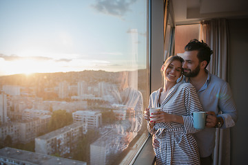 Image showing young couple enjoying evening coffee by the window