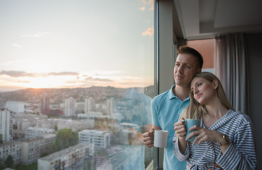 Image showing young couple enjoying evening coffee by the window