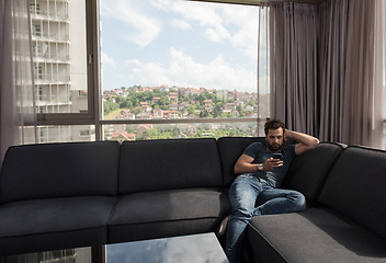 Image showing young casual man using a mobile phone at home