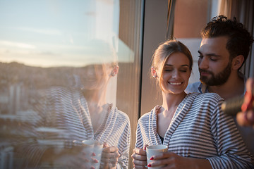 Image showing young couple enjoying evening coffee by the window