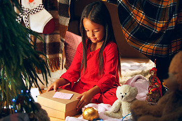 Image showing Merry Christmas and Happy Holidays. Cute little child girl writes the letter to Santa Claus near Christmas tree