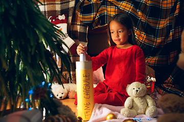 Image showing Merry Christmas and Happy Holidays. Cute little child girl writes the letter to Santa Claus near Christmas tree