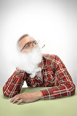 Image showing Handsome hipster man smoking cigarette at home. Man looking upwards and enjoying spending free time.